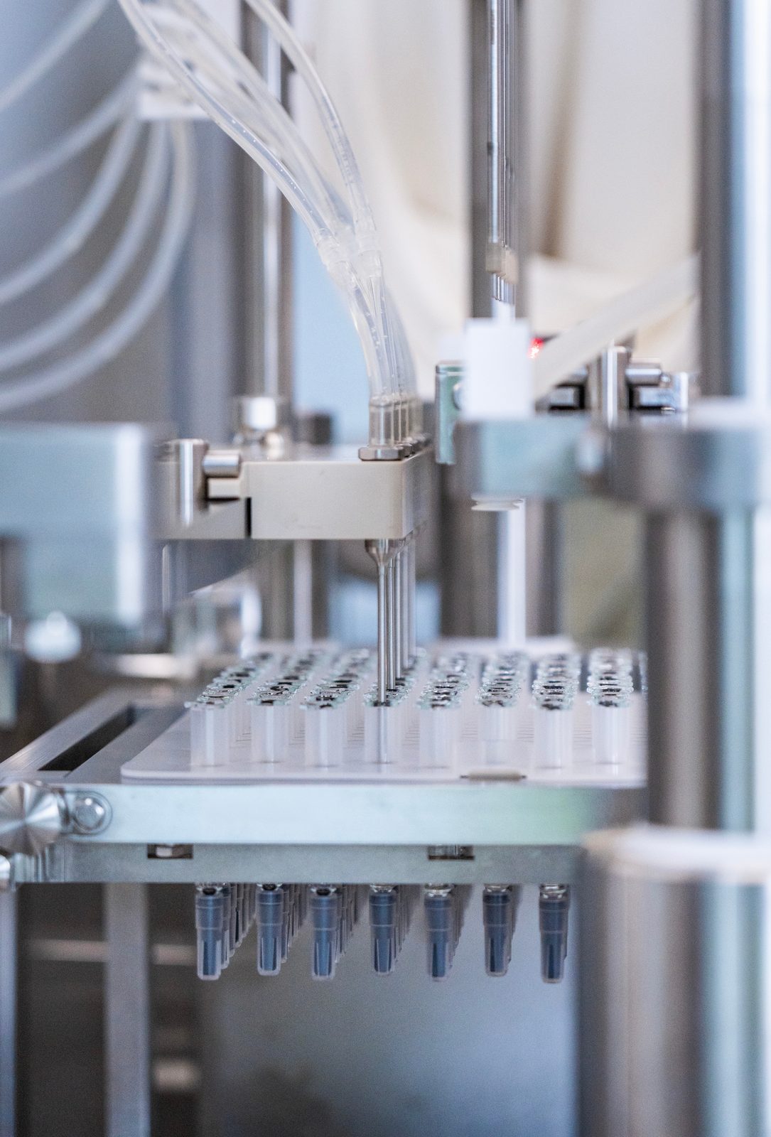 Automated syringe filling line seating stoppers into a nested tray of pre-filled syringes